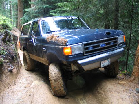 1991 Ford Bronco - This 1991 Ford Bronco navigates a challenging muddy path through a dense forest.
