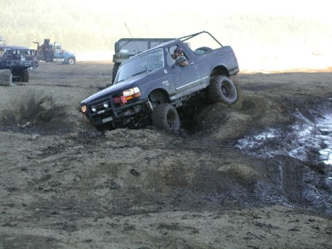 1993 Ford Bronco - This 1993 Ford Bronco is navigating a challenging off-road course with steep inclines and muddy terrain.