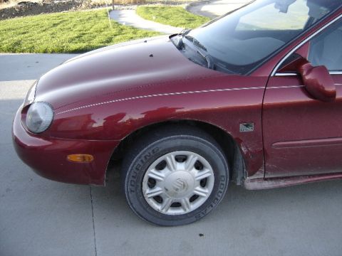 1998 Mercury Sable - Close-up of a maroon sedan's front passenger side, showing the wheel and fender.