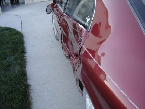 1998 Mercury Sable - Side view of a damaged red car door, showing significant body damage.