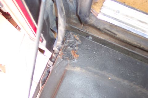 1986 Ford Bronco - Rust is forming on the body panel of a vehicle, near a red stripe.