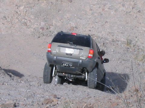 1995 Ford Bronco - A Jeep Grand Cherokee navigates a rocky, off-road trail from a rear perspective.