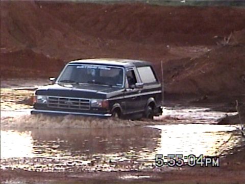 1988 Ford Bronco - This 1988 Ford Bronco is navigating a muddy off-road course, kicking up water as it goes.