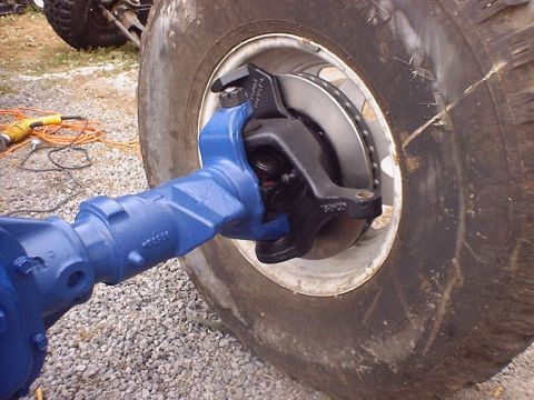 1988 Ford Bronco - Close-up of a vehicle's front axle assembly, showing the brake components and a large tire.