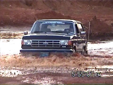 1988 Ford Bronco - This 1988 Ford Bronco is navigating through a muddy terrain, showing its off-road capability.