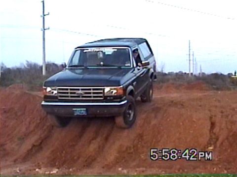 1988 Ford Bronco - A dark blue Ford Bronco navigates a dirt hill, captured on camera at 5:58 PM.