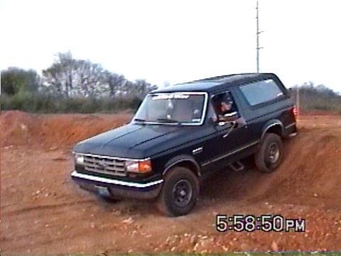 1988 Ford Bronco - This dark blue SUV navigates a dirt incline, appearing to be from the 1987 model year.