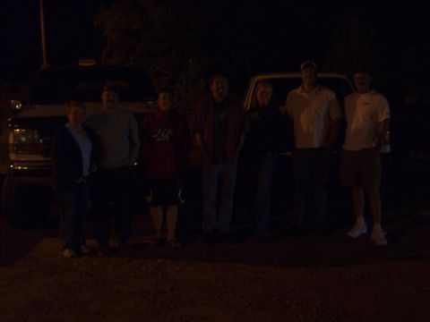 1996 Ford Bronco - Several people pose for a photo in front of two trucks at night.