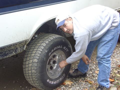 1996 Ford Bronco - A man inspects the tire of a 1996 Ford Bronco, which appears to be a side view.