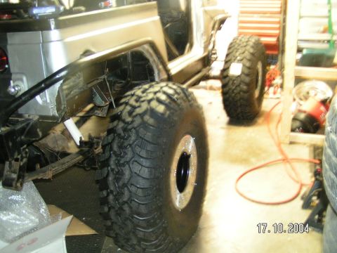 1978 Ford Bronco - An off-road vehicle is partially visible in a garage, with large tires and exposed body panels.