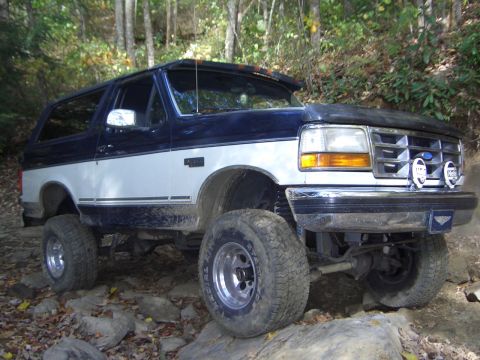1996 Ford Bronco - A lifted Ford Bronco navigates a wooded, rocky path.