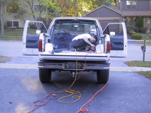 1993 Ford Bronco - A person is working on the interior of a white Ford truck with all doors open and power cords laid out.