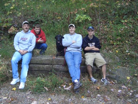 1996 Ford Bronco - A group of friends and their dog pose for a photo while sitting on a log in a wooded area.