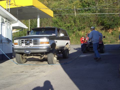 1996 Ford Bronco - A two-tone Ford Bronco is parked at a gas station, with a red ATV nearby.