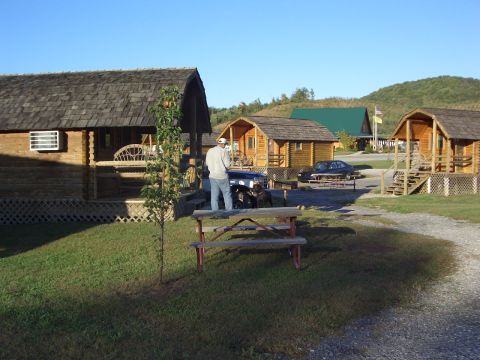 1996 Ford Bronco - A view of a campground with several log cabins and a parked car under a clear blue sky.