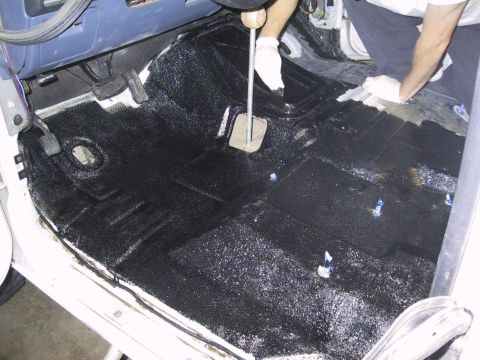 1993 Ford Bronco - Someone is applying a protective coating to the interior floor of a vehicle.
