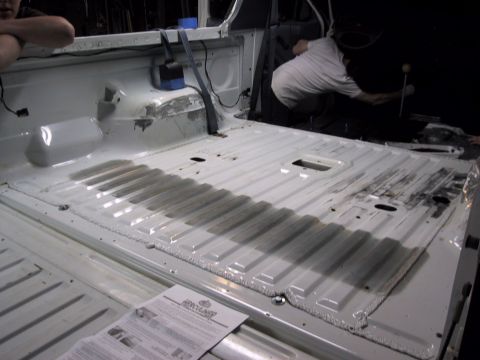 1993 Ford Bronco - A person works inside the white interior of a truck, with an instruction manual visible on the floor.