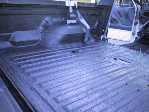 1993 Ford Bronco - Interior view of a 1993 Ford Bronco truck bed, showing the spray-on liner and a seatbelt.
