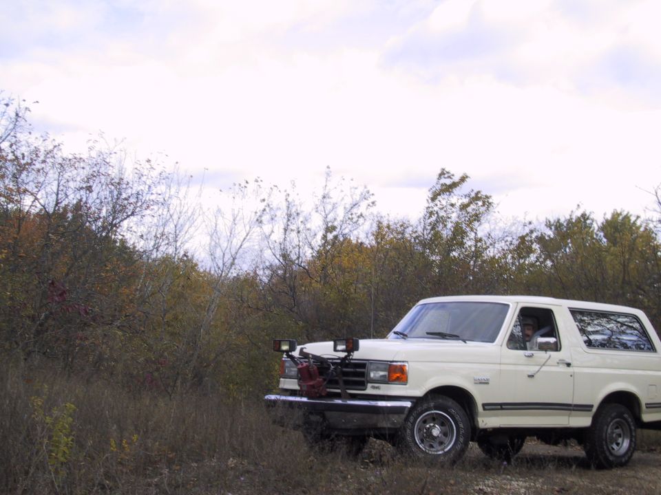 1993 Ford Bronco parked off-road with auxiliary lights and a red gas can on the front bumper