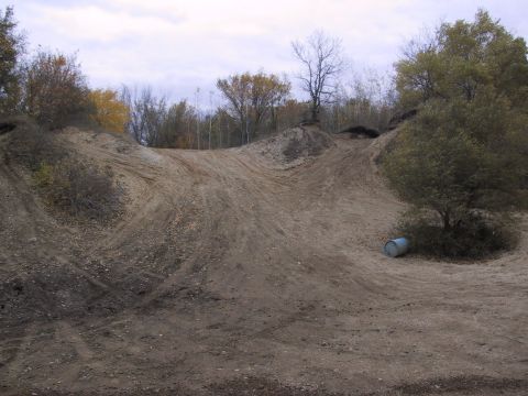 1993 Ford Bronco - A dirt track with tire marks and a barrel is visible under a tree.