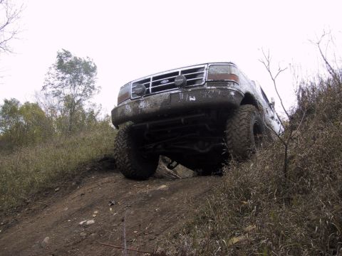 1993 Ford Bronco - This Ford Bronco is covered in mud as it navigates a steep, grassy incline.