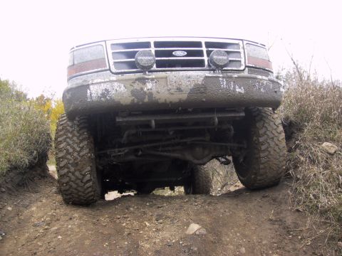 1993 Ford Bronco - This 1993 Ford Bronco navigates a muddy off-road trail, its front grille and tires.