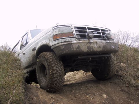 1993 Ford Bronco - Ford Bronco navigates a muddy off-road trail with large tires.