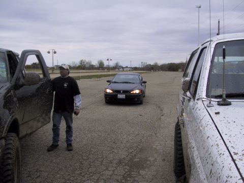 1993 Ford Bronco - Three vehicles and a man are parked in an open lot under an overcast sky.