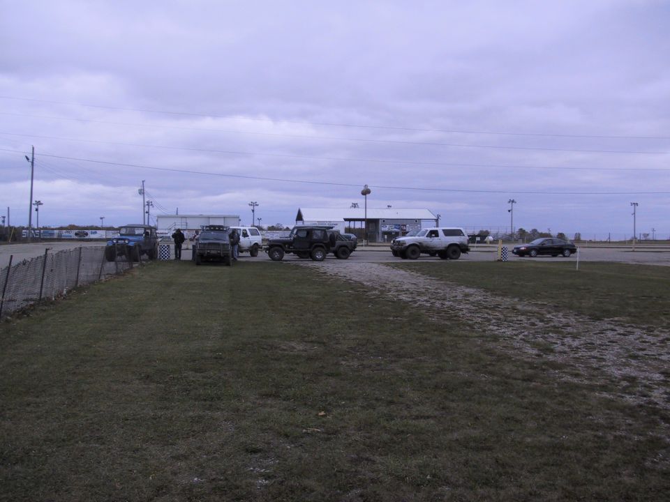 White SUV with off-road tires parked on dirt, other SUVs and a black car in background