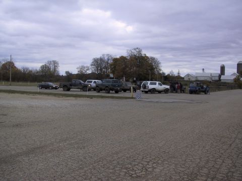1993 Ford Bronco - A white 1993 Ford Bronco is seen parked in a lot alongside other trucks and SUVs, with farm buildings in the background.
