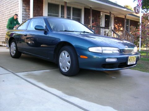 1995 Nissan 240SX - A blue 1995 Nissan 240SX coupe is parked on a concrete driveway in front of a house.