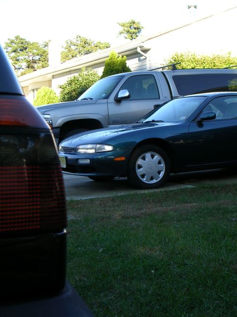 1995 Nissan 240SX - A dark green coupe is parked next to a silver pickup truck in a driveway.