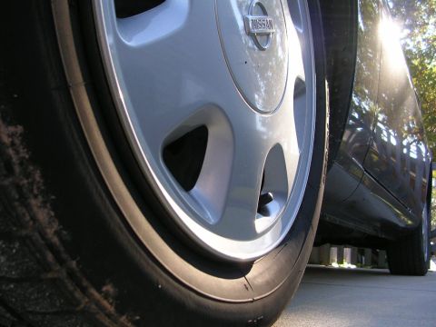 1995 Nissan 240SX - Close-up of the wheel and side of a 1995 Nissan 240SX, showing the Nissan badge on the hubcap.