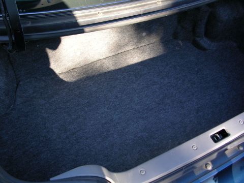 1995 Nissan 240SX - The interior of a car's trunk is shown, gray carpeting and a visible latch mechanism.
