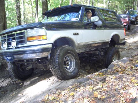 1993 Ford Bronco - A lifted Ford Bronco navigates a rocky trail with other vehicles behind it.