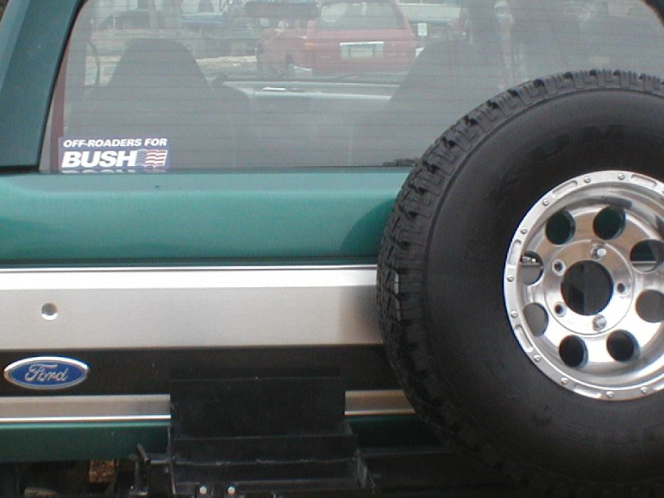 Green 1979 Ford Bronco II with a spare tire mounted on the rear door and a "Bush" sticker