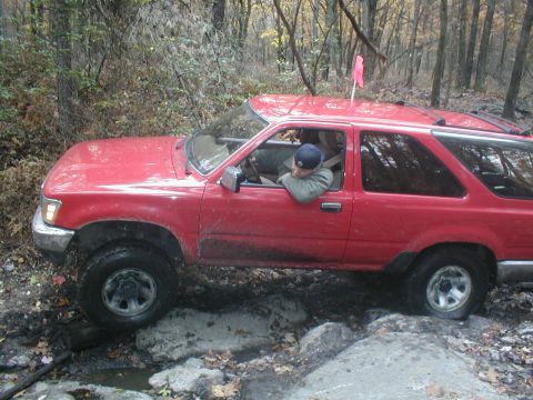 1979 Ford Bronco II - Red SUV driving over rocks off-road.