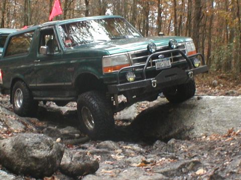 1979 Ford Bronco II - Green SUV with aftermarket modifications tackles a challenging rocky trail.
