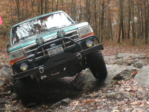 1979 Ford Bronco II - A green Ford Bronco tackles a rocky trail in an autumn forest.