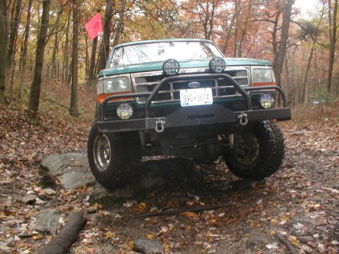 1979 Ford Bronco II - This green SUV navigates a rocky, wooded trail, its off-road modifications.