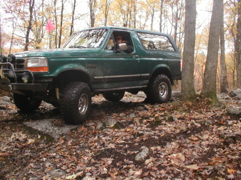 1979 Ford Bronco II - Ford Bronco navigating a rocky, wooded trail during autumn.