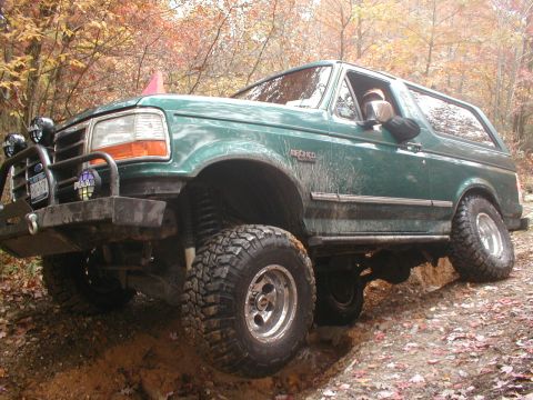1979 Ford Bronco II - Ford Bronco navigating a challenging off-road trail with autumn foliage in the background.