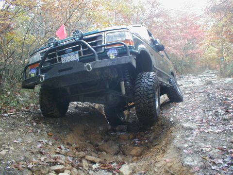 1979 Ford Bronco II - A lifted Ford Bronco navigates a challenging off-road path with large rocks and steep inclines.