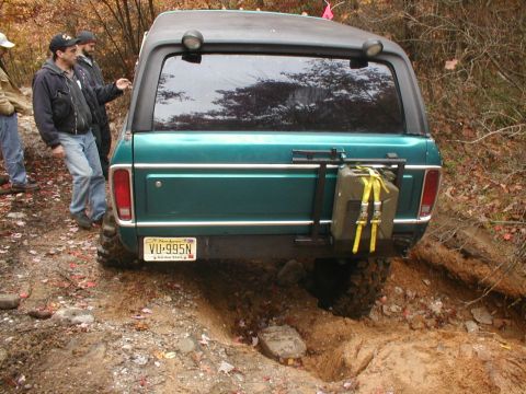 1979 Ford Bronco II - Rear view of a green 1979 Ford Bronco II off-roading with a spare gas can mounted on the back.