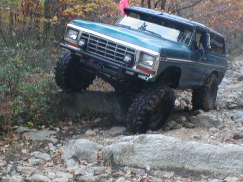 1979 Ford Bronco II - This modified SUV is shown off-roading on a rocky trail during autumn.