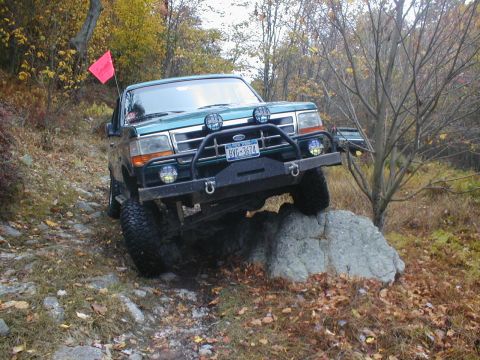 1979 Ford Bronco II - Ford Bronco navigates a rock obstacle on an off-road trail during autumn.
