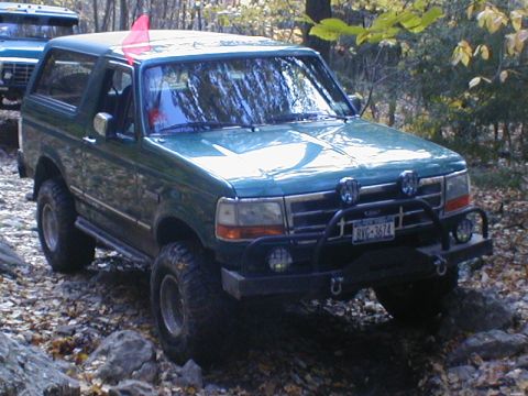 1979 Ford Bronco II - A green SUV navigates a rocky trail with another vehicle visible behind it.