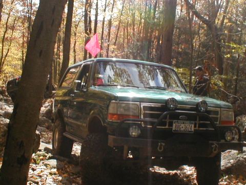1979 Ford Bronco II - This green SUV navigates a rocky, wooded trail during autumn.