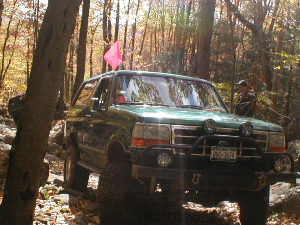 Green SUV with off-road modifications on a rocky trail