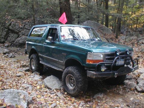 1979 Ford Bronco II - This Ford Bronco is navigating a challenging off-road trail covered in rocks and fallen leaves.